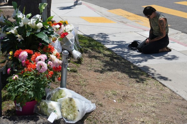 Nicole Witherow prays beside flowers placed outside of the Islamic Center of San Diego, the day after a shooting, Tuesday, May 19, 2026, in San Diego. (AP Photo/Jae C. Hong)