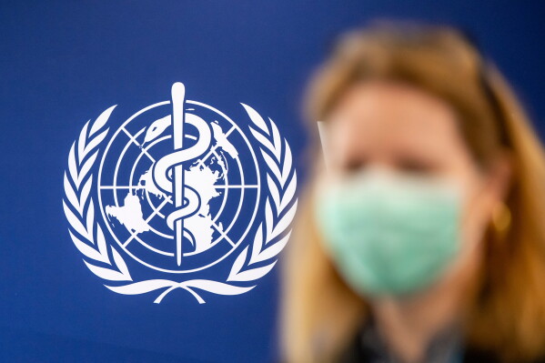 A person is wearing a protective face mask in front of the WHO logo, during the media regarding the epidemic of Ebola disease, during a press conference at the World Health Organization (WHO) headquarters in Geneva, Switzerland, Friday, May 22, 2026. (Martial Trezzini/Keystone via AP)