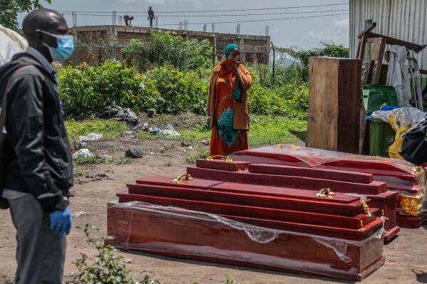 Family members of people who died of Ebola stand next to coffins at a health center in Rwampara, Congo, Wednesday, May 20, 2026. (AP Photo/Moses Sawasawa)
