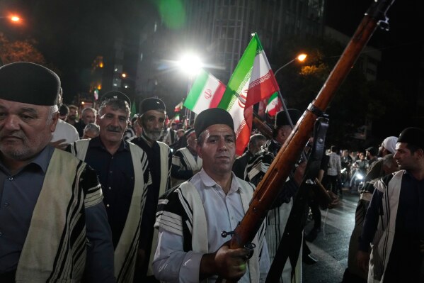 Bakhtiari nomads, wearing traditional dress, chant slogans as one of them holds a gun during a pro-government gathering on Monday, May 18, 2026, near the residence where former Iranian Supreme Leader Ayatollah Ali Khamenei was killed in U.S. and Israeli strikes in Tehran, Iran. (AP Photo/Vahid Salemi)